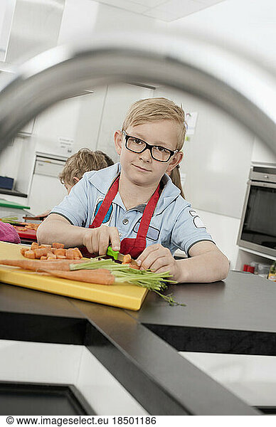 Two schoolboys cutting vegetables in home economics class  Bavaria  Germany