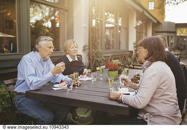 Two senior couples having desserts at outdoor restaurant