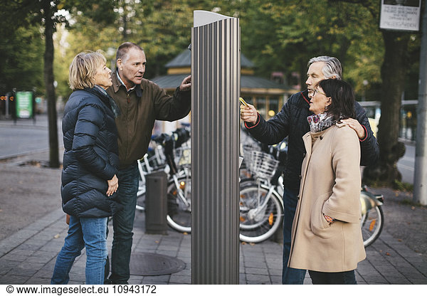Two senior couples making payment at bike rental station