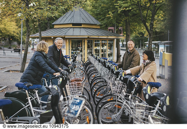 Two senior couples taking rental bikes at parking lot