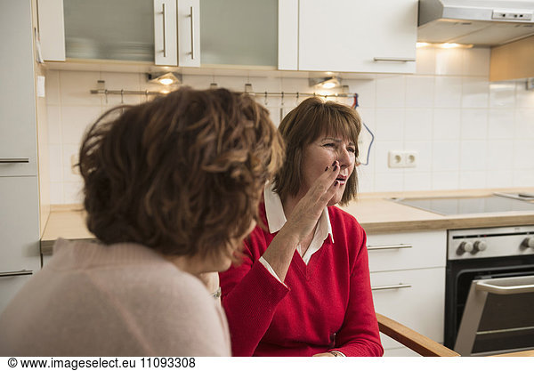 Two senior woman talking in kitchen