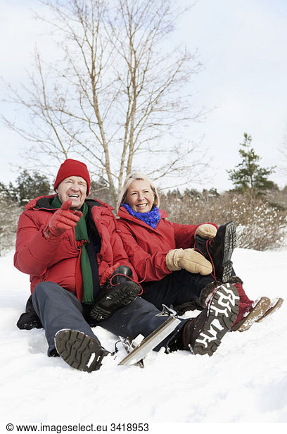 Two seniors sitting outdoors in the snow