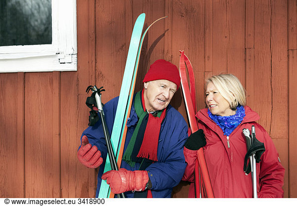 Two seniors standing outdoors with their skis