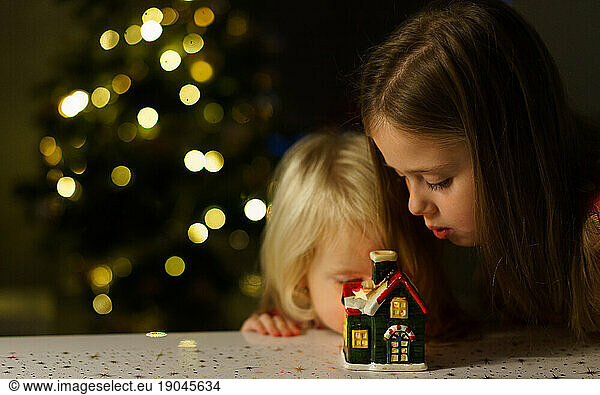 two sisters looking a small house Christmas light