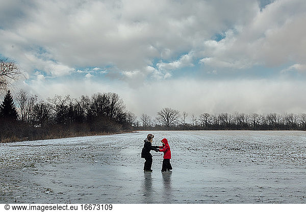 two sisters playing on a frozen farm field in winter