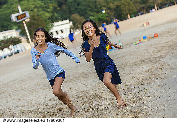 Two sisters racing on Repulse Bay Beach; Hong Kong  China