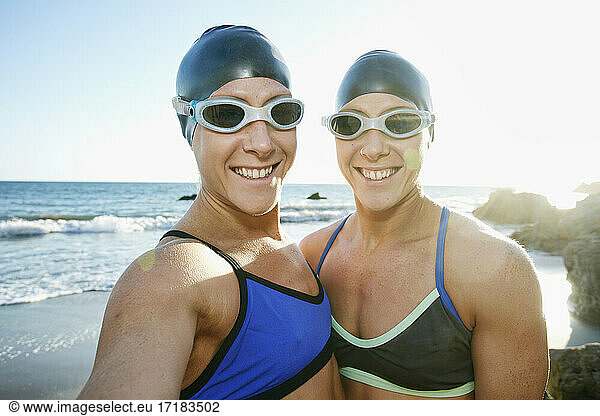 Two sisters  triathletes in training in swimwear  swimhats and goggles.