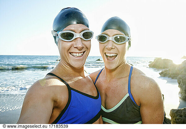 Two sisters  triathletes in training in swimwear  swimhats and goggles.