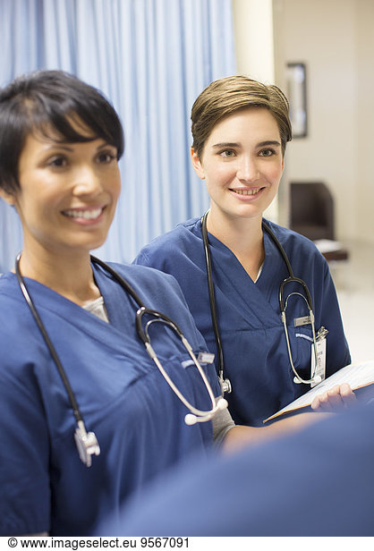 two-smiling-doctors-wearing-scrubs-with-stethoscopes-around-necks-in