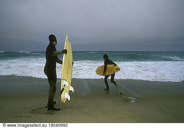 Two surfers run into the ocean  Cape Cod  Massachusetts.