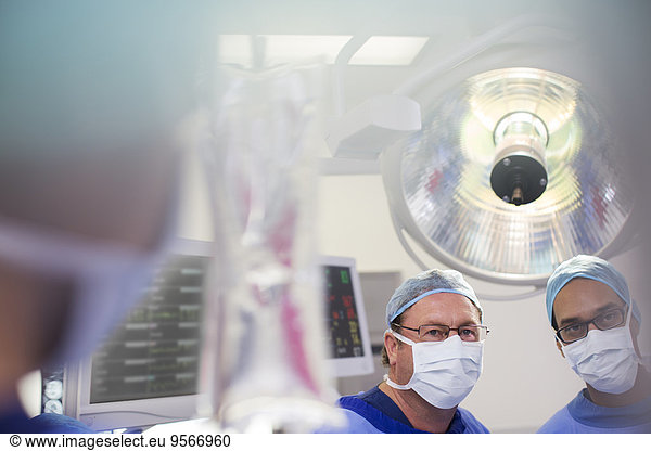 Two surgeons looking at saline bag during surgery