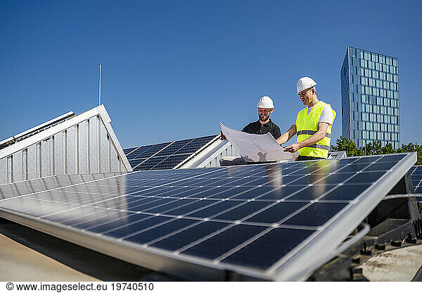 Two technicians strategizing on the rooftop of a solar-powered company building