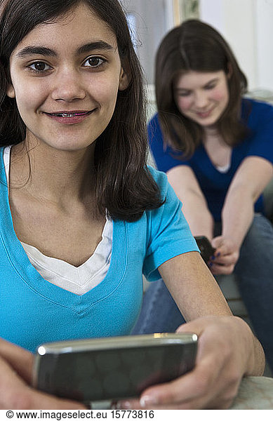 Two teenage girls using smart phones