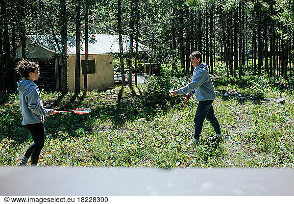 Two teenagers playing badminton outside at campground