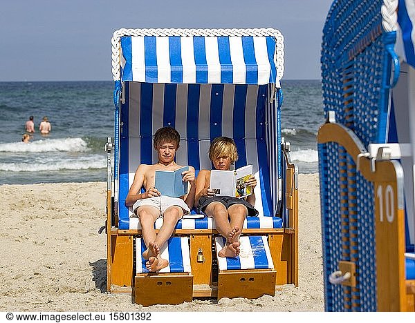 Two teenagers sit in a wicker beach chair and read a book  Kühlungsborn  Baltic Sea  Mecklenburg-Vorpommern  Germany  Europe