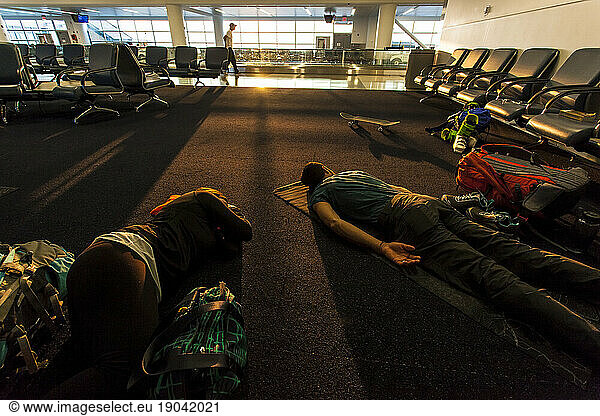 Two Travelers Who Just Took An Overnight Flight Sleeping On The Airport Floor