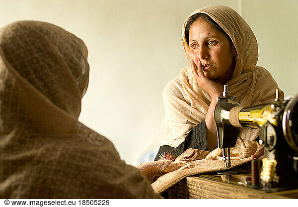 Two women chat while they do their sewing work in a Kabul business.
