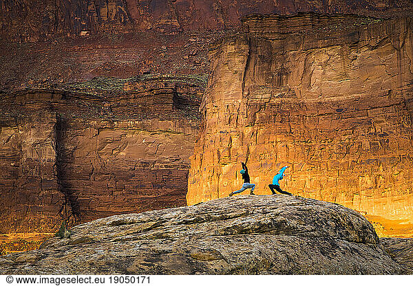 Two women doing yoga outdoors in the desert at sunrise.