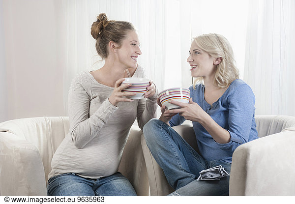 Two women drinking tee talking chair at home