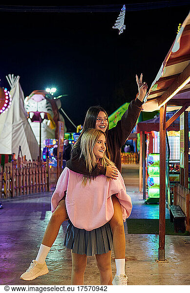 Two women friends have a good time at a funfair at night