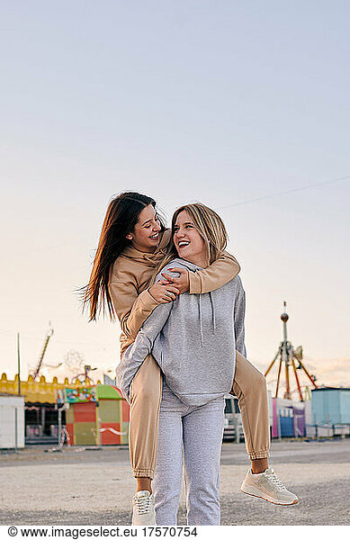Two women friends have a good time at a funfair at sunset