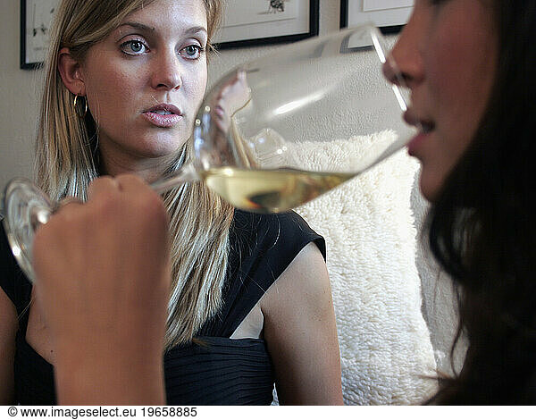 Two women have a conversation over wine at a party.