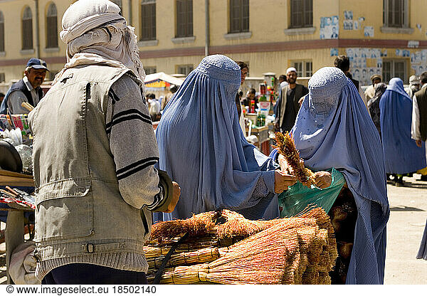 Two women in burqas shop for brooms near Mandawi Market in Kabul.