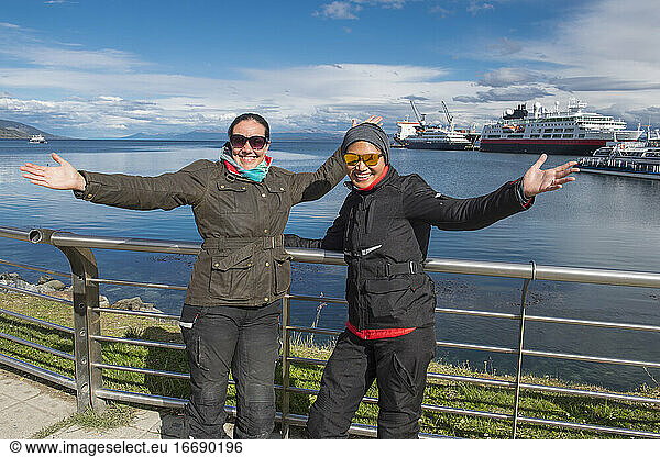Two women in motorbike clothes posing at the harbour of Ushuaia