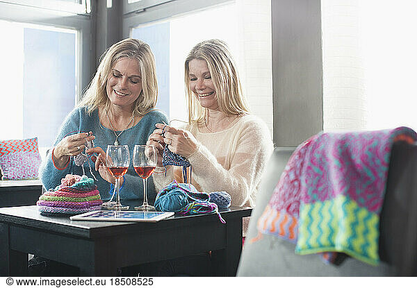 Two women knitting muffler and drinking wine in coffee shop and smiling  Bavaria  Germany
