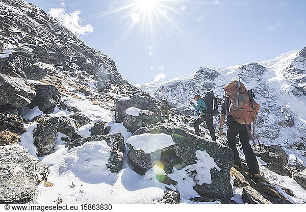 Two women mountaineers ascend through a snowy boulder field