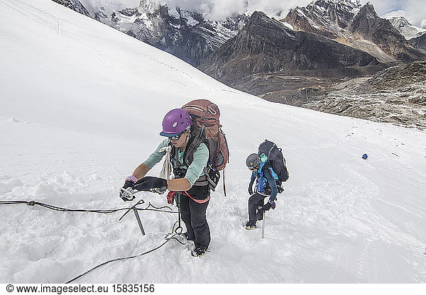 Two women mountaineers practice steep snow skills on a glacier