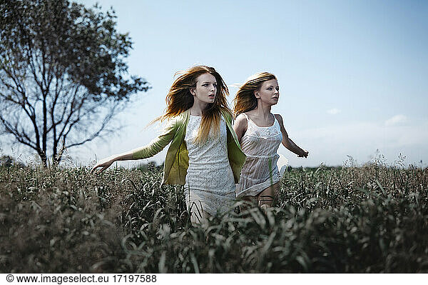 Two women running in the grassland. Nicely fits for book cover