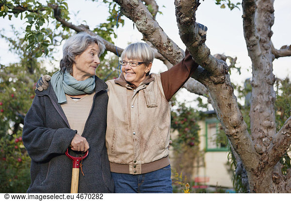Two women standing beside tree