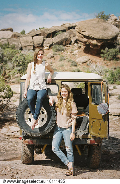 Two women standing by a 4x4 on a mountain road.