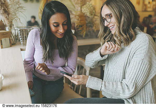 Two women using smartphone in a cafe