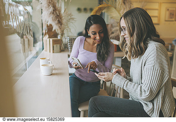 Two women using smartphones in a cafe