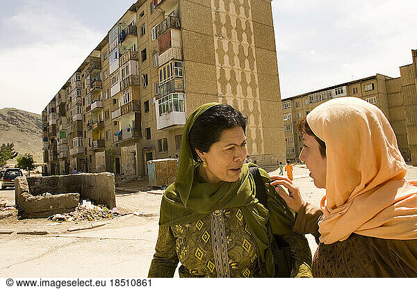 Two women walk outside apartment blocks in Kabul.