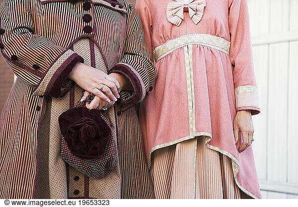 Two women wearing vintage dresses.