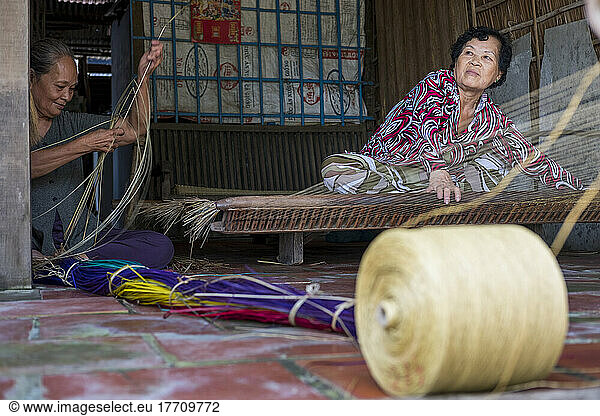 Two women work together to weave a rattan mat in Vietnam; Binh Thanh Island  Vietnam