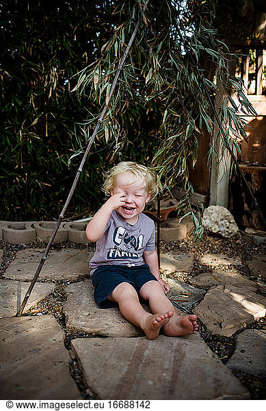 Two Year Old Boy Sitting Under Bamboo Laughing