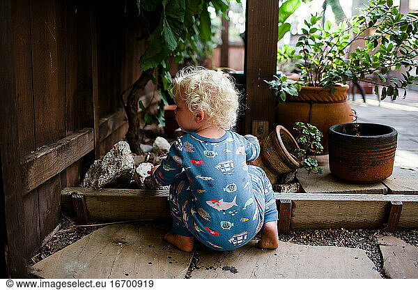 Two Year Old in Pajamas Crouching Under Grapevine
