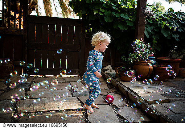 Two Year Old in Pajamas Running Through Bubbles in Front Yard
