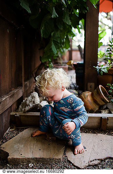Two Year Old in Pajamas Sitting on Rocks in Front Yard
