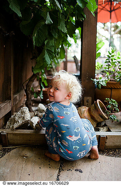 Two Year Old Looking Over Shoulder While Crouching Under Grapevine