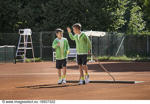 Two young boys preparing tennis court  Bavaria  Germany