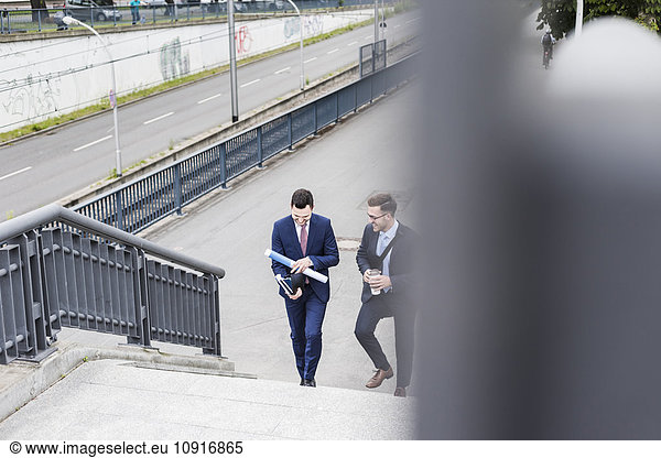 Two young businessmen walking together in the city