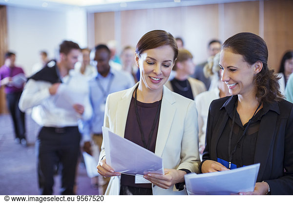 Two young businesswoman looking through files in conference room