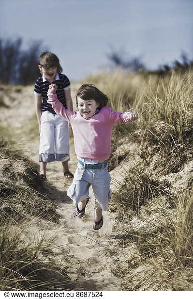 Two young children playing in the dunes.
