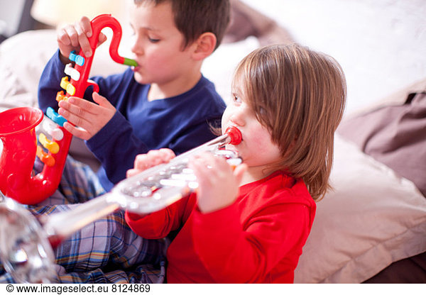 Two young children playing toy instruments