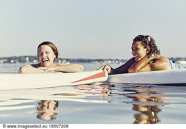 Two young female friends on standup paddle board in Casco Bay  Maine